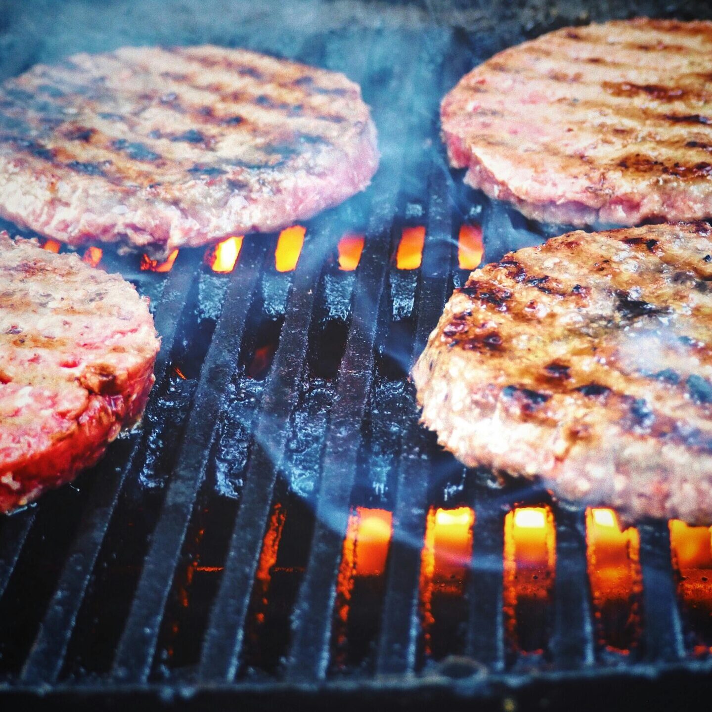 Juicy beef patties cooking on a hot grill, perfect for barbecue cookouts.